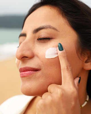 Mulher aplicando o protetor solar facial Anasol FPS 70 Clareador no rosto na praia