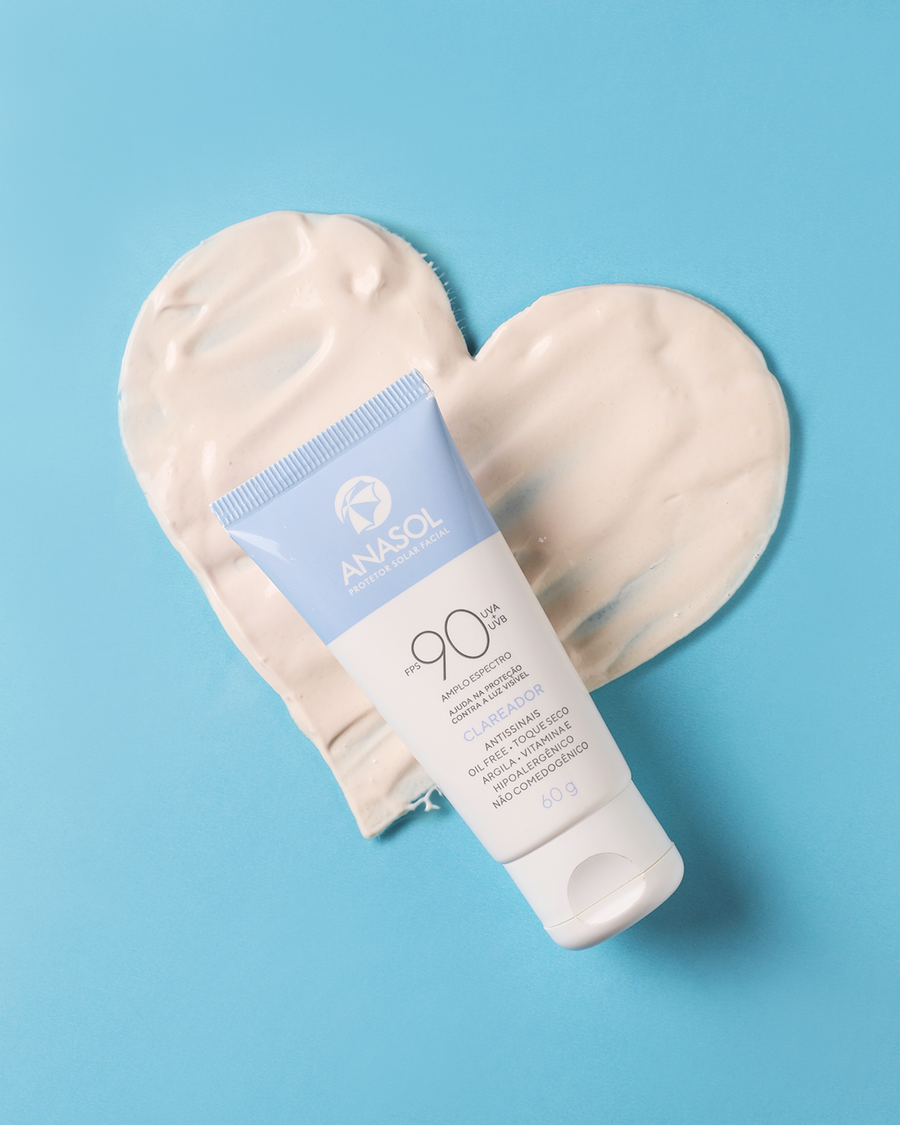 A bisnaga do Clareador FPS 90 deitada sobre um coração de creme branco, em fundo azul.