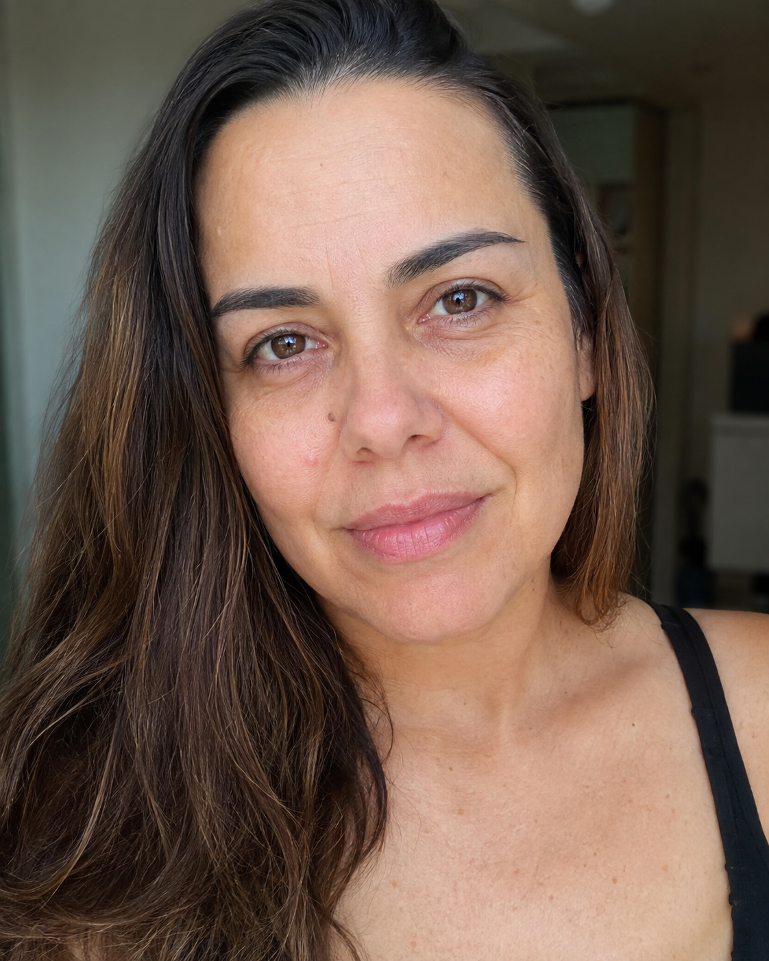Mulher de uns quarenta anos, sem maquiagem, com as linhas e a sombra da área dos olhos à mostra