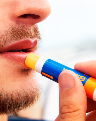 Homem aplicando o protetor solar labial Anasol AN Sport FPS 60 nos lábios