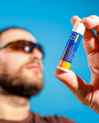 Homem segurando o protetor solar labial Anasol AN Sport FPS 60
