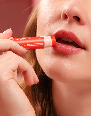 Modelo aplicando o Lipstick Frutas Vermelhas Hidrabene nos lábios