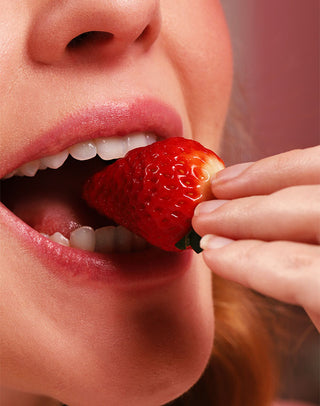 Mulher comendo morango em referência ao aroma do Lipstick Hidrabene