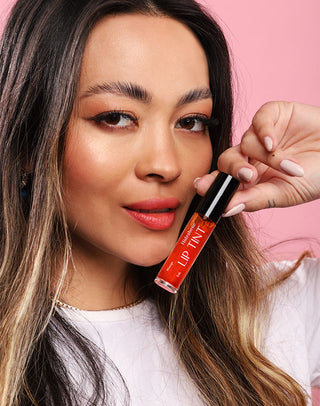 Modelo segurando o Lip Tint Pêssego Hidrabene com os lábios em tom pêssego