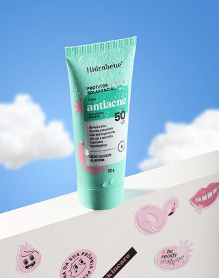 Protetor Solar Antiacne FPS 50 Hidrabene com gotas de água em pé sobre uma bancada branca com adesivos divertidos