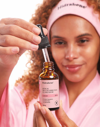 Mulher segurando o conta-gotas do Sérum Multicorretivo Clareador Hidrabene