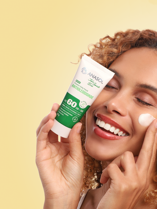 Mulher sorrindo aplicando o protetor solar facial Anasol Todo Santo Dia FPS 60 no rosto
