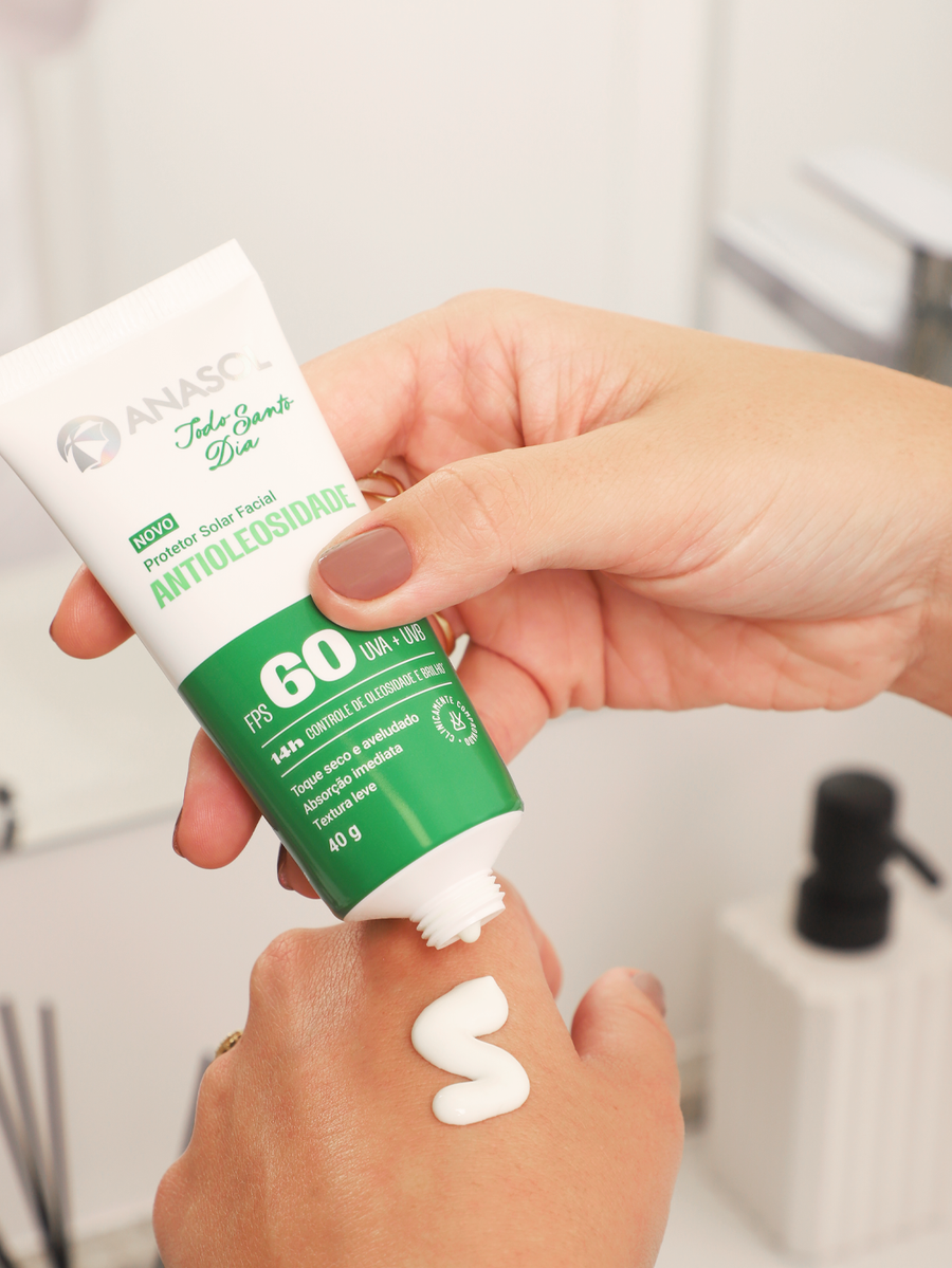 Mão apertando a bisnaga do Antioleosidade FPS 60 e depositando o creme nas costas da outra mão.